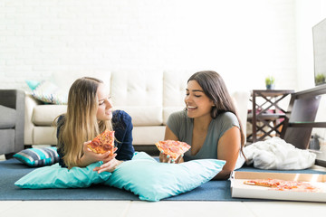 Women Holding Pizza Slices While Lying On Floor During Party