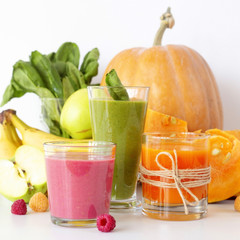 Autumnal vegetable and fruit smoothies on a white background next to pumpkin, spinach, banana, raspberries and apples. Diet, Detox and Vegetarian Food
