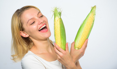Woman hold yellow corncob on white background. Girl playful mood hold ripe corns in hands. Food vegetarian and healthy natural organic product. Corn crop harvest concept. Vegetarian nutrition concept