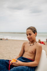 Wet boy holding apricot on the beach