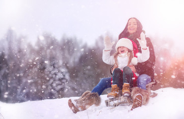 A winter fairy tale, a young mother and her daughter ride a sled