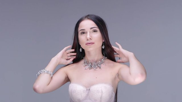 Beautiful woman posing in studio. She shows women's jewelry