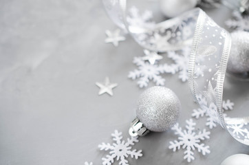 Silver Christmas background. Curly ribbon with decorative balls and snowflakes.