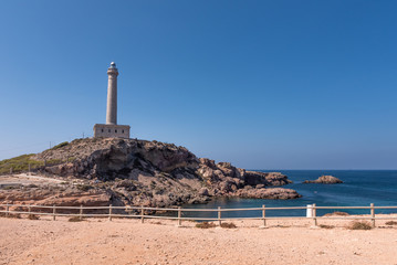 Fototapeta na wymiar Lighthouse of Cabo de Palos, cape in the Spanish municipality of Cartagena, in the region of Murcia. It is summer, and the sky is a deep blue