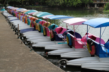 Closeup of duck boats lie at the pier of lake in public park in sunny day.