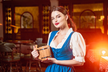Young beautiful girl with a wooden mug of beer in hands at a party Oktoberfest.