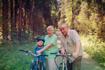 active senior couple with little granddaughter on bikes in nature