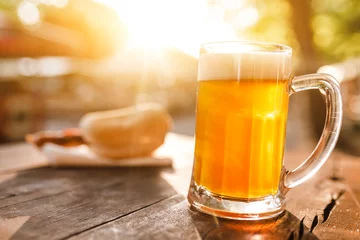 Küchenrückwand glas motiv kalter Glaskrug Bier mit Schaum mit Bratwurst Hotdog mit Sonnenstrahlen © EdNurg