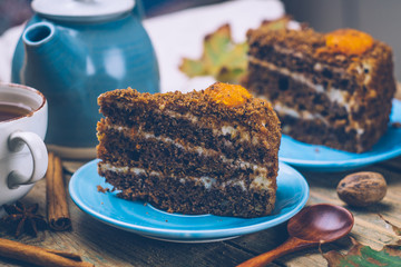 Carrot cake (homemade desserts) whith cinnamon sticks and decorated with spices and cup of tea on wooden background.