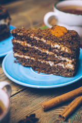 Carrot cake (homemade desserts) whith cinnamon sticks and decorated with spices and cup of tea on wooden background.