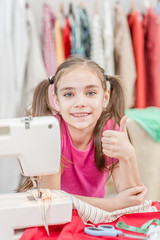 happy girl at workplace seamstress showing thumbs up. Hobby sewing concept