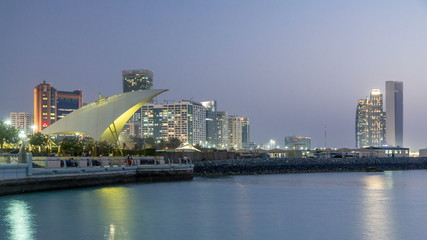 Promenade in Abu Dhabi illuminated at dusk, day to night timelapse.