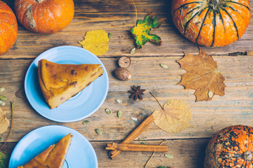 Homemade sliced pumpkin tart pie recipe whith cinnamon, nuts and fresh pumpkin on vintage table wooden table background. Halloween party traditional dessert. Rustic style.