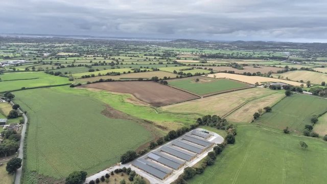 Aerial view, semi panorama panning move. Sewage works, houses among fields on Cheshire countryside. Tarvin in background