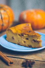 Homemade sliced pumpkin tart pie recipe whith cinnamon, nuts and fresh pumpkin on vintage table wooden table background. Halloween party traditional dessert. Rustic style.