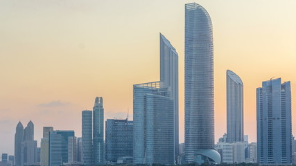 Abu Dhabi city skyline with skyscrapers before sunrise with water reflection night to day timelapse