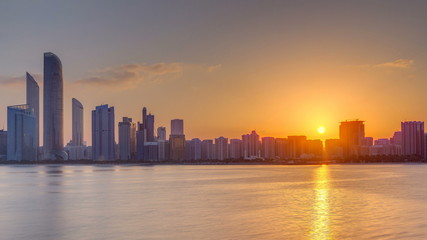 Obraz premium Abu Dhabi city skyline on sunrise time with water reflection timelapse.