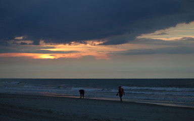 Friends walking down the beach looking for sea shells on a sun rise