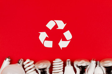 Old used metal led, incandescent halogen cfi fluorescent, lumens light bulbs tube on red background. Reuse recycling sign symbol environment light bulbs concept. - Powered by Adobe