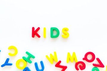 Early childhood development concept. Word kids written by plastic letters of toy alphabet on white background top view copy space