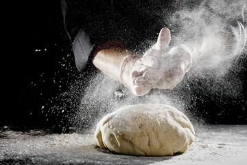 Man sprinkling white flour over blob of dough - obrazy, fototapety, plakaty