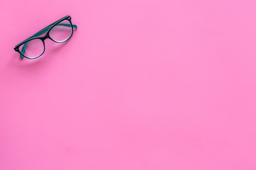 Glasses with transparent optical lenses on pink background top view copy space