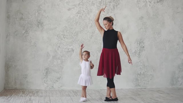 a small ballerina repeats the movements behind the teacher. ballet lesson in the studio