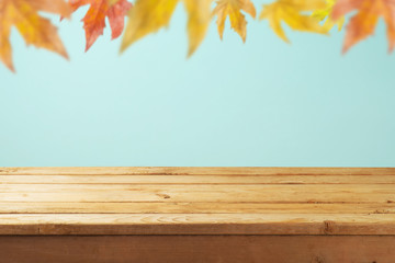 Empty wooden table over autumn leaves blurred background