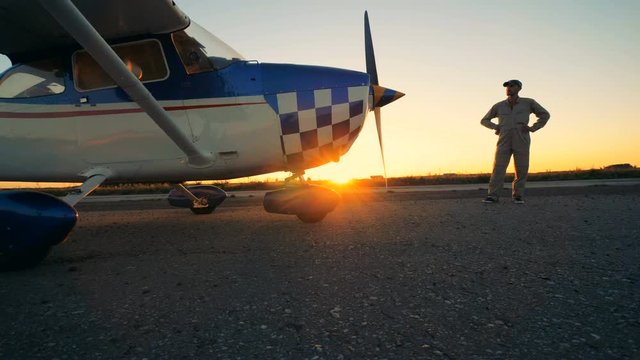 A man looks at his aircraft. One pilot stands near a plane on a runway.