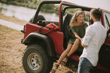 Young woman and man having fun outdoor near car