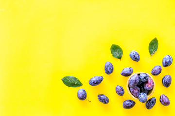 Blue plum for dessert. Purple plum and leaves pattern on yellow background top view copy space