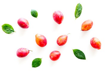 Summer harvest of red plum.  Red plum and leaves pattern on white background top view