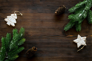 Spruce branch, cones and vintage toys in shape of spruce and stars on dark wooden background for decoration on chrismas or new year top view copy space
