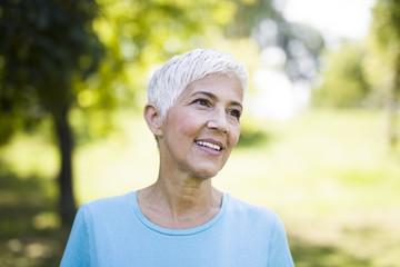 Naklejka na ściany i meble Portrait of a smiling sporty senior woman in a park