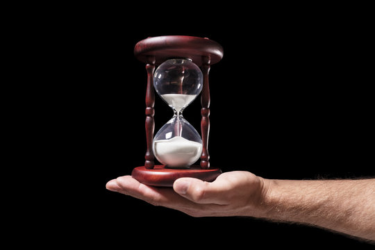  Hand holding hourglass over black background