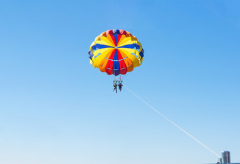 Happy couple Parasailing in Dominicana beach in summer. Couple under parachute hanging mid air. Having fun. Tropical Paradise. Positive human emotions, feelings, family, children, travel, vacation.