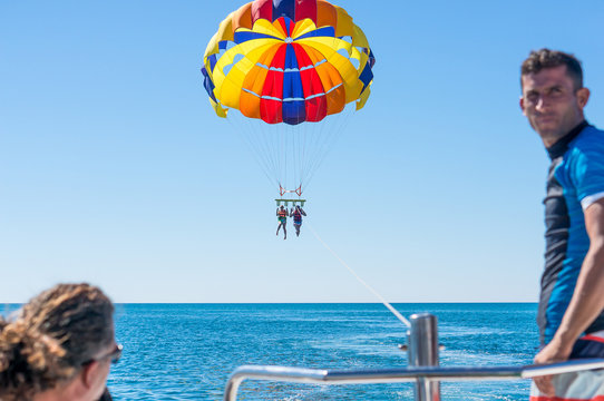 Happy couple Parasailing in Dominicana beach in summer. Couple under parachute hanging mid air. Having fun. Tropical Paradise. Positive human emotions, feelings, family, children, travel, vacation.