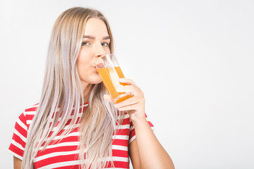Portrait of a beautiful woman holding orange juice glass. Smiling girl isolated portrait over...