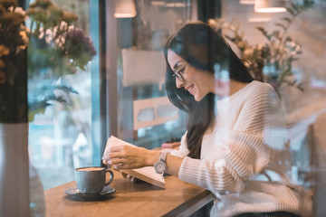 smiling woman reading book at table with coffee cup in cafe