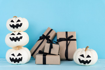 White ghost pumpkin with gift box and bat on sky blue background. halloween concept.