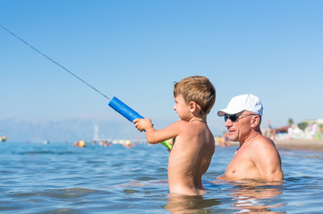 Happy family. Smiling grandfather and grandson playing at the sea. Positive human emotions, feelings, joy.