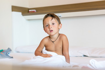 Obraz na płótnie Canvas Little baby boy waked up and sitting on the white bed