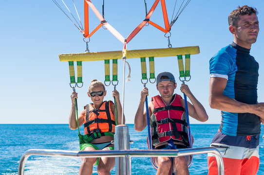 Happy couple Parasailing in Dominicana beach in summer. Couple under parachute hanging mid air. Having fun. Tropical Paradise. Positive human emotions, feelings, family, children, travel, vacation. 