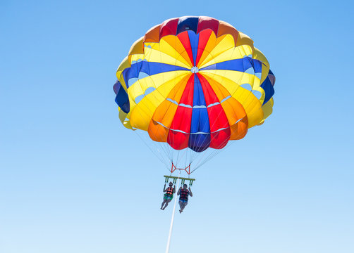 Happy couple Parasailing in Dominicana beach in summer. Couple under parachute hanging mid air. Having fun. Tropical Paradise. Positive human emotions, feelings, family, children, travel, vacation.
