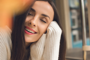 close up portrait of attractive young woman with closed eyes in cafe