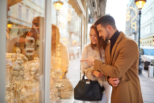 A beautiful young couple walking on the street and checking the storefront with christmas decoration.