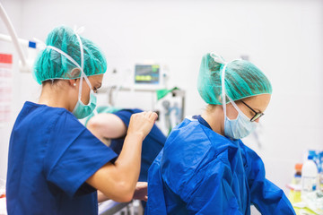 Surgeon and assistant preparing for surgery - obrazy, fototapety, plakaty