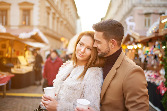 A beautiful young couple drinking mulled wine in a christmas market.