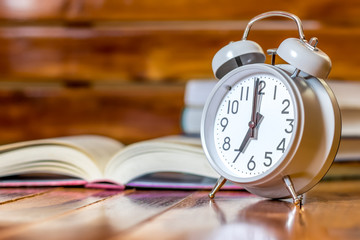 Concept education student and reading book.Wake up Alarm clock 7.00 and reading book on wood table with sunrise.Image is Blurry.