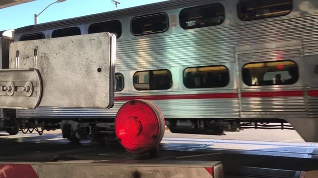A double-decker commuter rail train passes by closed safety gates in San Francisco, California